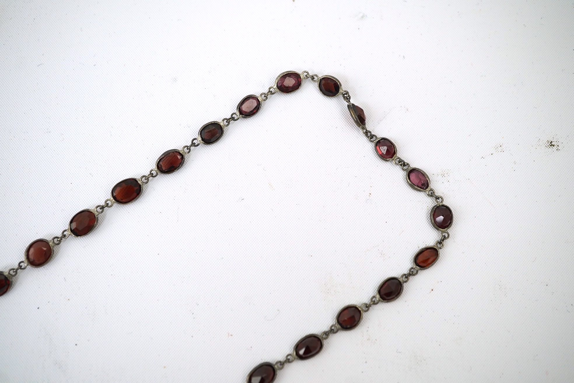 A Victorian silver and graduated oval cut two colour garnet set drop spectacle necklace, 74cm. Condition - poor to fair